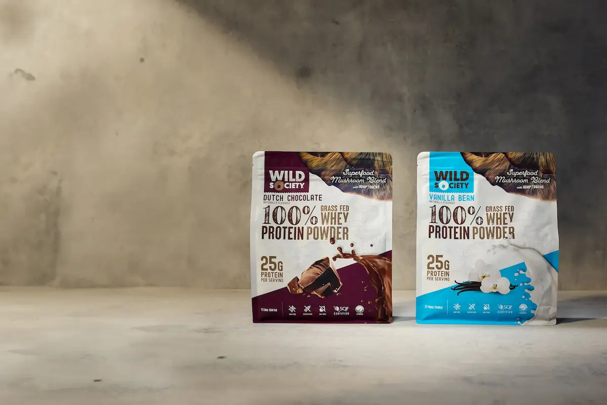 Two packages of Wild Society protein powder on a neutral background